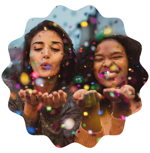two women blowing confetti
